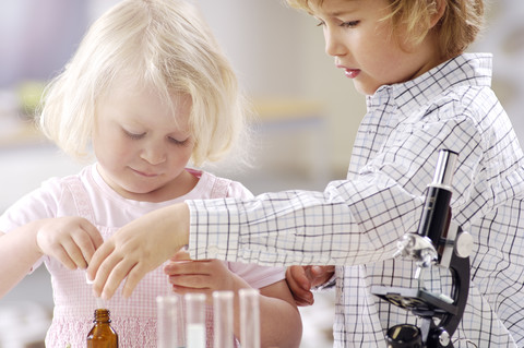 Zwei kleine Kinder spielen mit Utensilien eines chemischen Labors, lizenzfreies Stockfoto