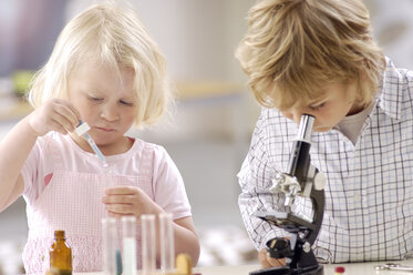 Zwei kleine Kinder spielen mit Utensilien eines chemischen Labors - GUFF000240