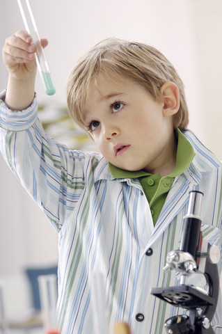 Porträt eines kleinen Jungen mit Reagenzglas und Mikroskop, lizenzfreies Stockfoto