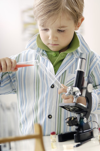 Porträt eines kleinen Jungen mit Reagenzgläsern und Mikroskop, lizenzfreies Stockfoto