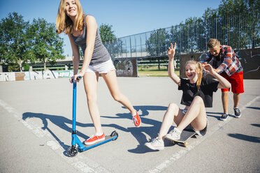 Drei verspielte Teenagerfreunde mit Roller und Skateboard - AIF000257
