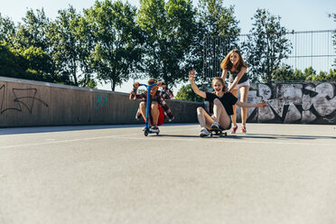 Three playful teenage friends with scooter and skateboard - AIF000262