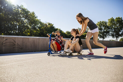 Drei verspielte Teenagerfreunde mit Roller und Skateboard - AIF000263