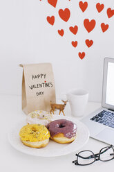 Stillleben mit Laptop, Donuts, Valentinstagsgeschenk und Herzen an der Wand - EBSF001231