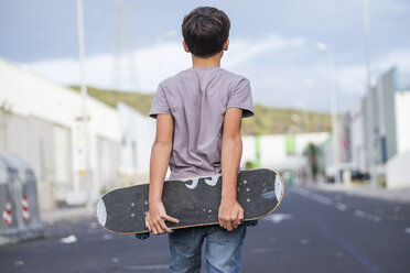 Spanien, Teneriffa, Rückenansicht eines Jungen, der sein Skateboard hinter seinem Rücken hält - SIPF000041