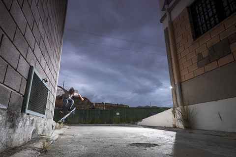 Spanien, Teneriffa, Junge beim Schlittschuhlaufen zwischen zwei Gebäuden, lizenzfreies Stockfoto