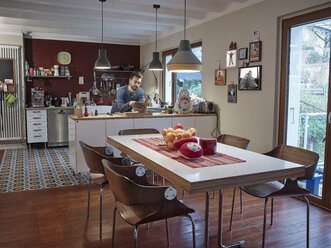 Young man using digital tablet in open plan kitchen - RHF001243