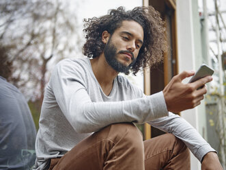 Junger Mann schaut auf sein Handy - RHF001260