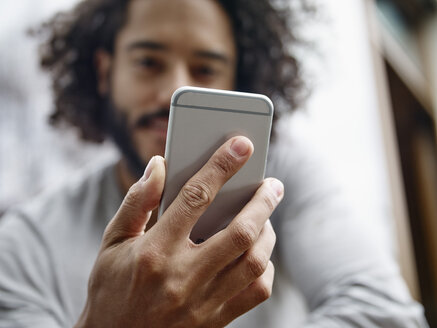 Junger Mann hält Mobiltelefon - RHF001262