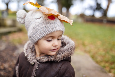 Portrait of little girl with autumn leaf on her wooly hat - MGOF001246