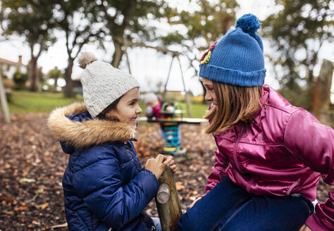 Zwei sprechende Mädchen auf einem Spielplatz im Herbst - MGOF001252
