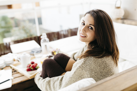Porträt einer lächelnden Frau, die auf einem Balkon sitzt, lizenzfreies Stockfoto