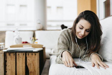 Relaxed woman listening music with earphones on balcony - JRFF000295