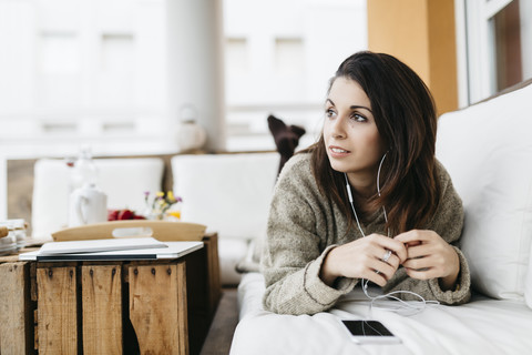 Porträt einer Frau, die auf dem Balkon mit Kopfhörern Musik hört, lizenzfreies Stockfoto