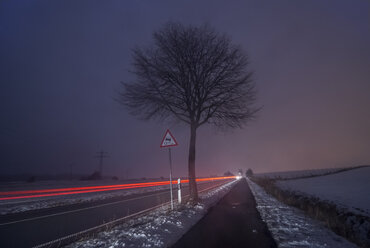 Deutschland, Niedersachsen, dribbelnde Autos auf der Straße, Nebel am Abend, Langzeitbelichtung - PVCF000740