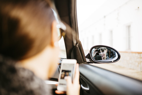 Weiblicher Beifahrer im Auto, der ein Smartphone benutzt, lizenzfreies Stockfoto