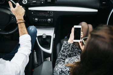 Junges Paar im Auto, Beifahrer benutzt Smartphone - JRFF000324