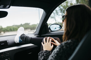 Weiblicher Beifahrer im Auto mit Fuß auf dem Armaturenbrett - JRFF000329