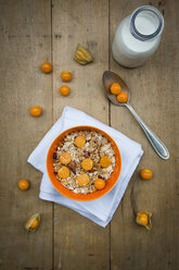 Bowl with cereals and physalis, milk bottle on wood - LVF004391