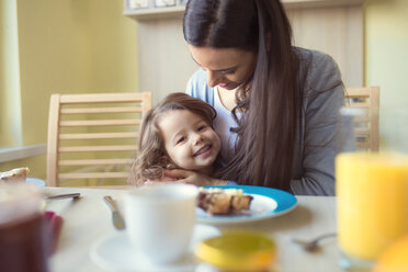 Portrait of smiling little girl and her mother at breakfast table - HAPF000115