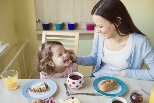 Porträt einer Mutter und ihrer kleinen Tochter, die sich am Frühstückstisch amüsieren - HAPF000119