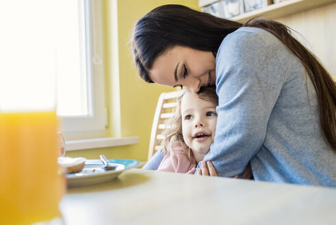 Mutter und ihre kleine Tochter kuscheln am Frühstückstisch - HAPF000122