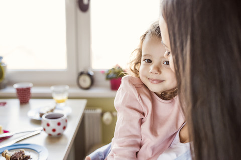 Porträt eines lächelnden kleinen Mädchens, das mit seiner Mutter kuschelt, lizenzfreies Stockfoto