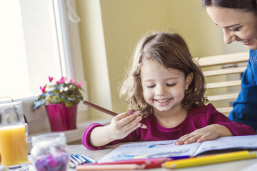 Portrait of smiling little girl painting with coloured pencils - HAPF000132