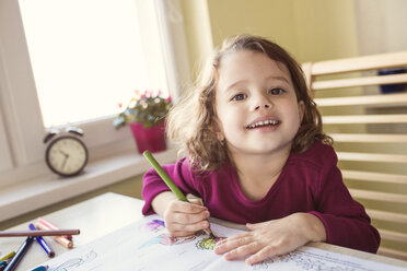 Portrait of smiling little girl painting with coloured pencils - HAPF000136