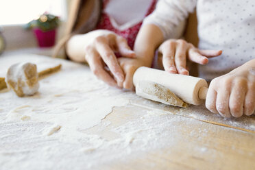 Mother helping her little daughter rolling out dough, close-up - HAPF000139