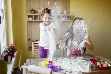 Mother and her little daughter throwing flour in the air at the kitchen - HAPF000157
