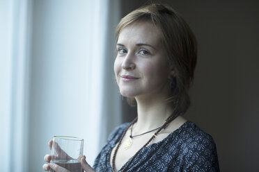 Portrait of smiling young woman with glass of water - SGF002003