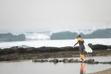 Spain, Tenerife, Boy walking on beach carrying surfboard - SIPF000057