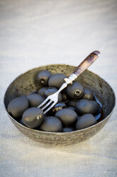 Metallschale mit schwarzen Oliven und Gabel auf Tuch - LVF004407