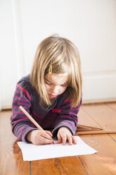 Little girl lying on the floor drawing something - LVF004421