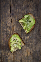 Slice of toasted bread with acocado, cress and hemp seeds on wood - LVF004424