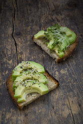 Slice of toasted bread with acocado, cress and hemp seeds on wood - LVF004426