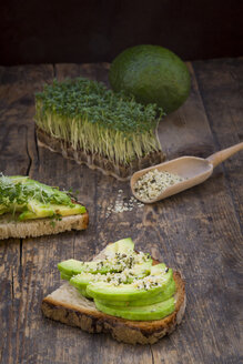 Halbe Scheibe getoastetes Brot mit Acocado und Hanfsamen auf Holz - LVF004428