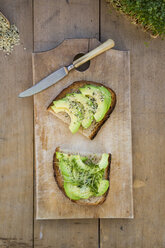 Getoastete Brotscheibe mit Acocado, Kresse und Hanfsamen auf Holzbrett - LVF004434