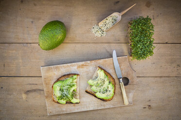 Getoastete Brotscheibe mit Acocado, Kresse und Hanfsamen auf Holzbrett - LVF004435