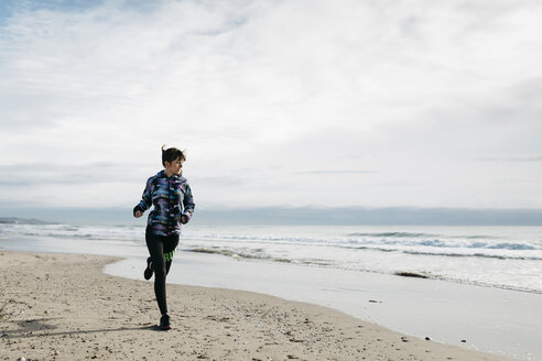 Spanien, Tarragona, Frau läuft im Winter am Strand - JRFF000340