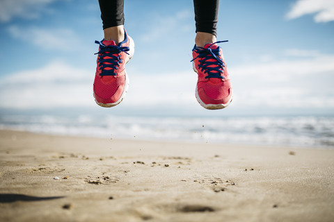 Feet of woman jumping on beach stock photo