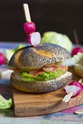 Poppy seed roll with cream cheese, lettuce leaf, salmon and onion rings garnished - YFF000513