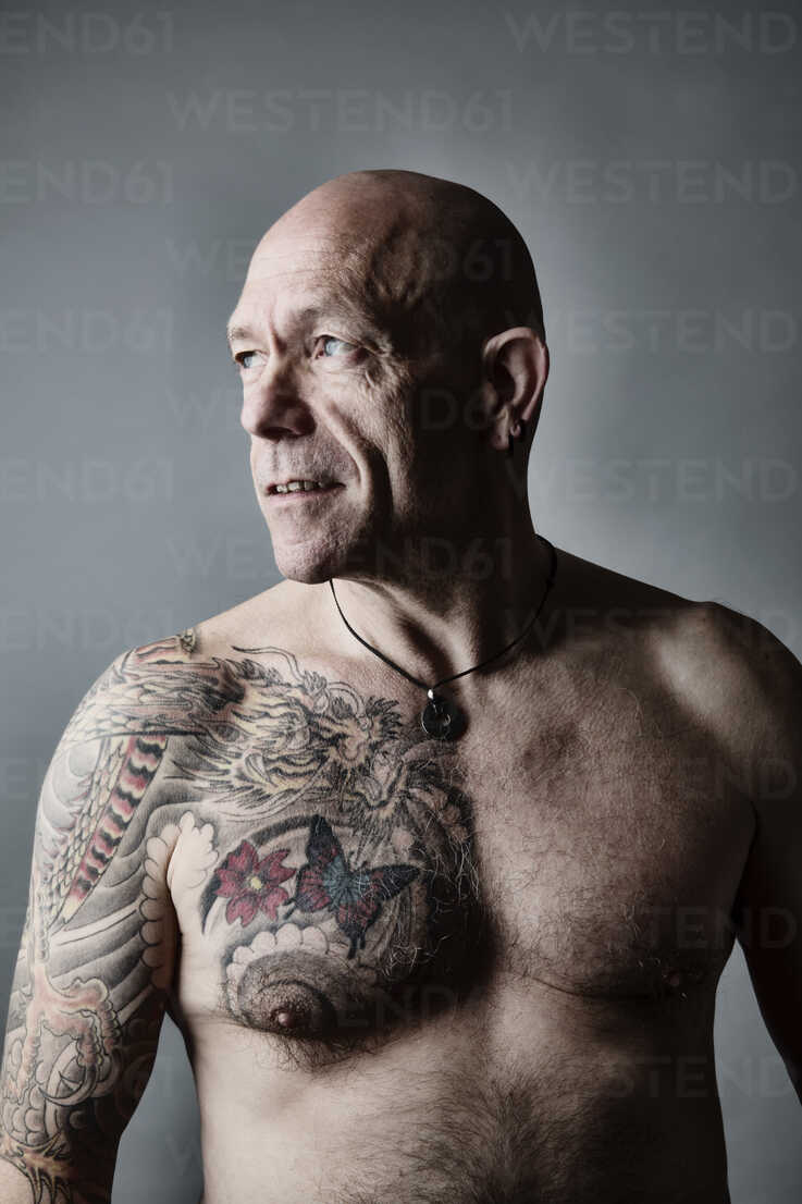 Portrait of angry bald man standing with … – License image