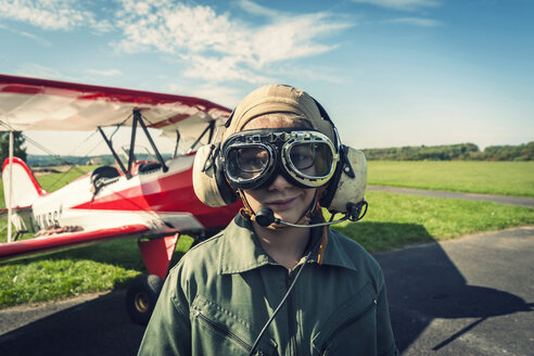 Germany, Dierdorf, Boy in front of biplane wearing old pilot outfit - PAF001538