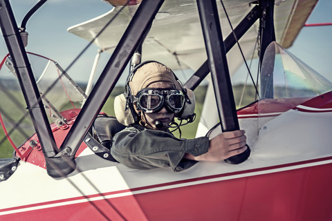 Germany, Dierdorf, Boy sitting in biplane wearing old pilot outfit stock photo