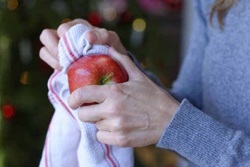 Hand einer Frau, die einen Weihnachtsapfel mit einem Küchentuch poliert, Nahaufnahme - LBF001347