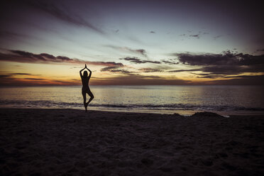 USA, Florida, Naples, Silhouette einer Frau beim Yoga am Strand, Sonnenuntergang - CHPF000196
