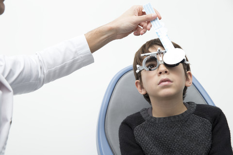 Optiker untersucht die Sehkraft eines Jungen, lizenzfreies Stockfoto