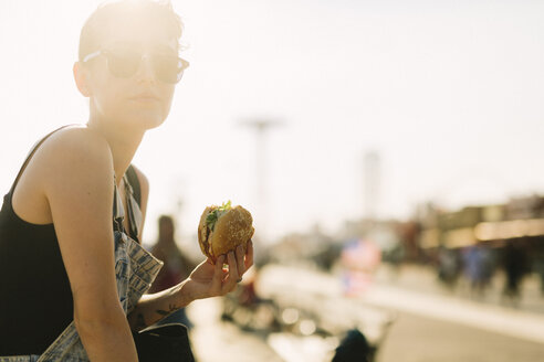 USA, New York, Coney Island, junge Frau beim Essen eines Hamburgers - GIOF000629